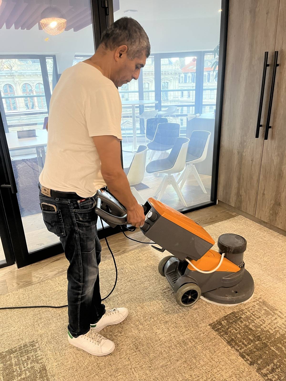 Agent ENI shampouinant la moquette d’un hall de bureaux